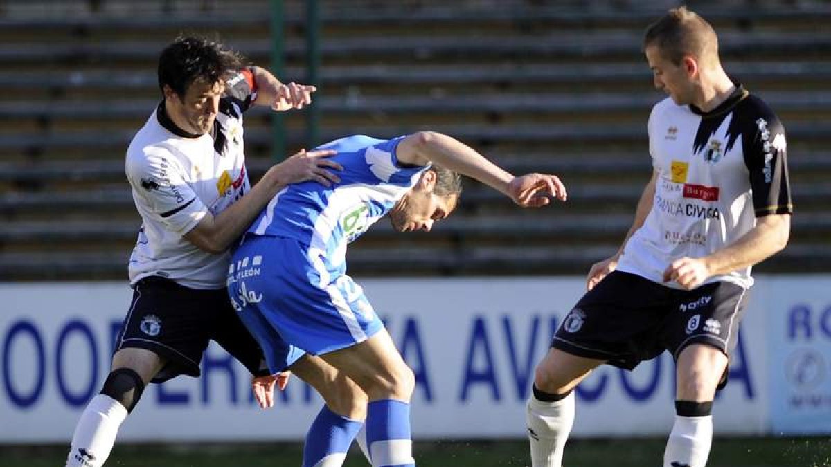 Javi Navarro pugna por el balón entre dos defensas.