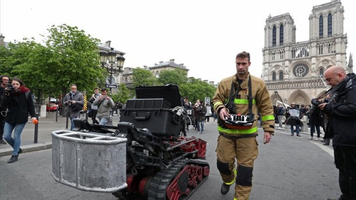 Un bombero, junto con el robot que ayudó a los bomberos en el incendio de Notre Dame, este martes.