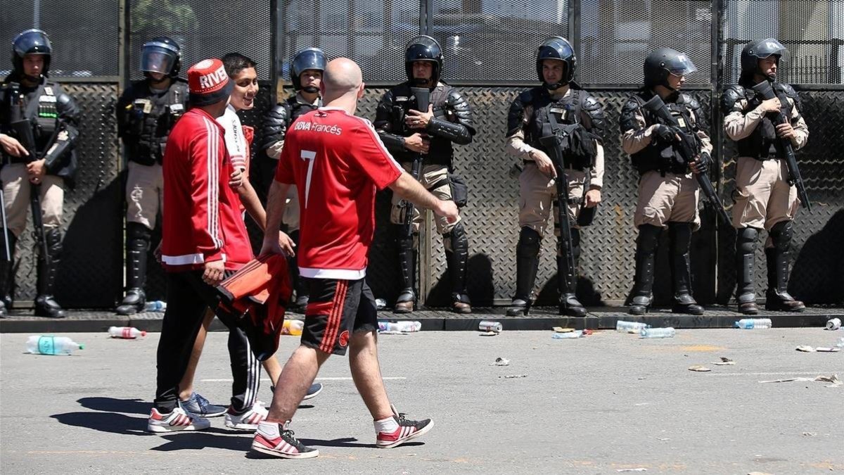 Aficionados del River pasan por delante de las fuerzas policiales tras la suspensión del partido el pasado sábado.