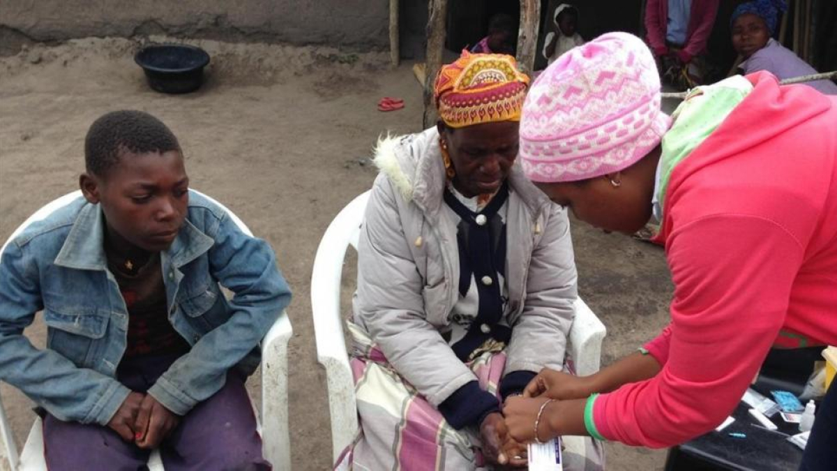 Gerlito (a la izquierda), el joven enfermo de malaria, mira como le hacen la prueba a su madre.