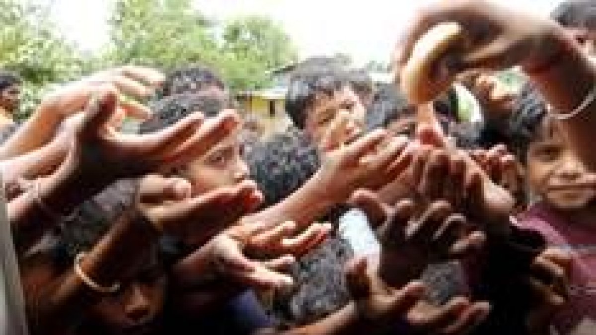 Unos niños hambrientos hacen cola para recibir un pedazo de pan en la India