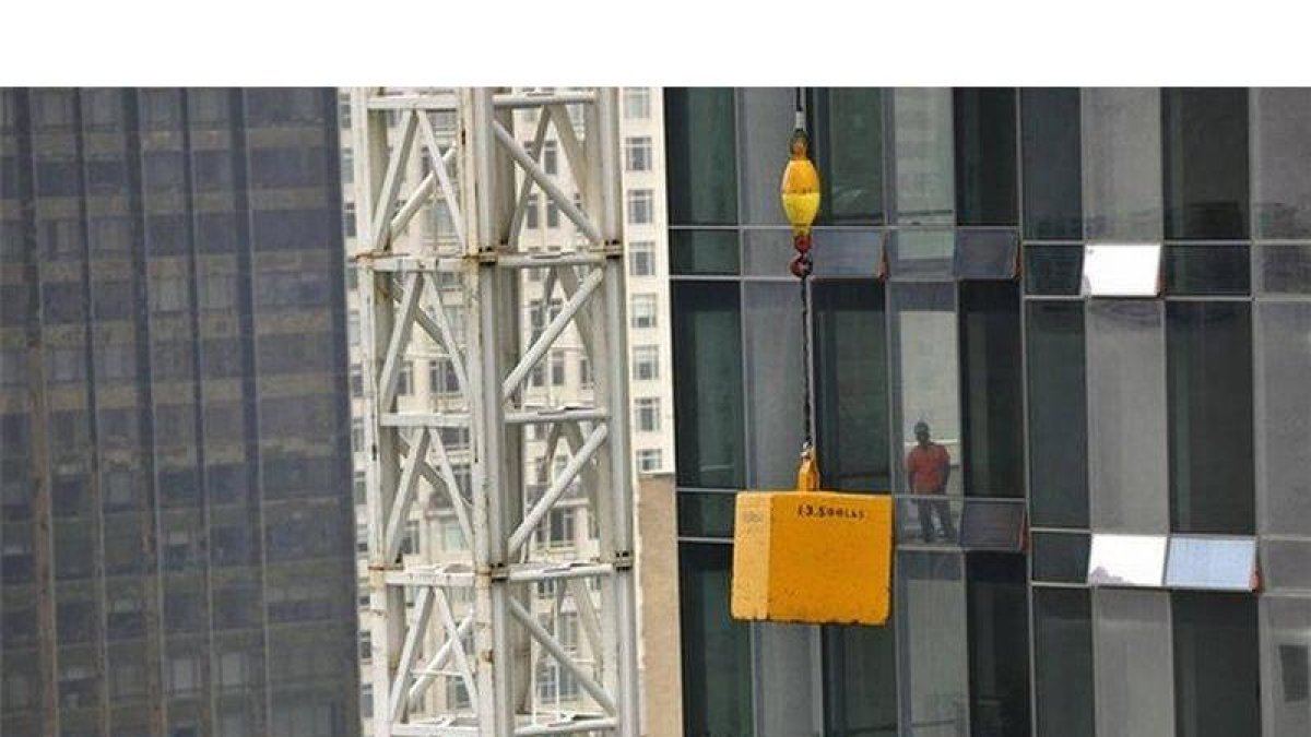 Un obrero contempla el contrapeso de la grúa colgado sobre la calle 57 de Manhattan.