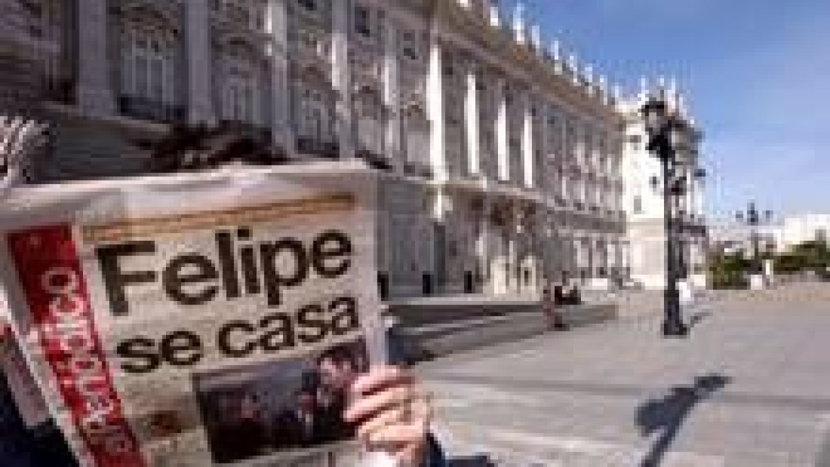Una persona lee un diario con la ya famosa noticia delante del Palacio de Oriente
