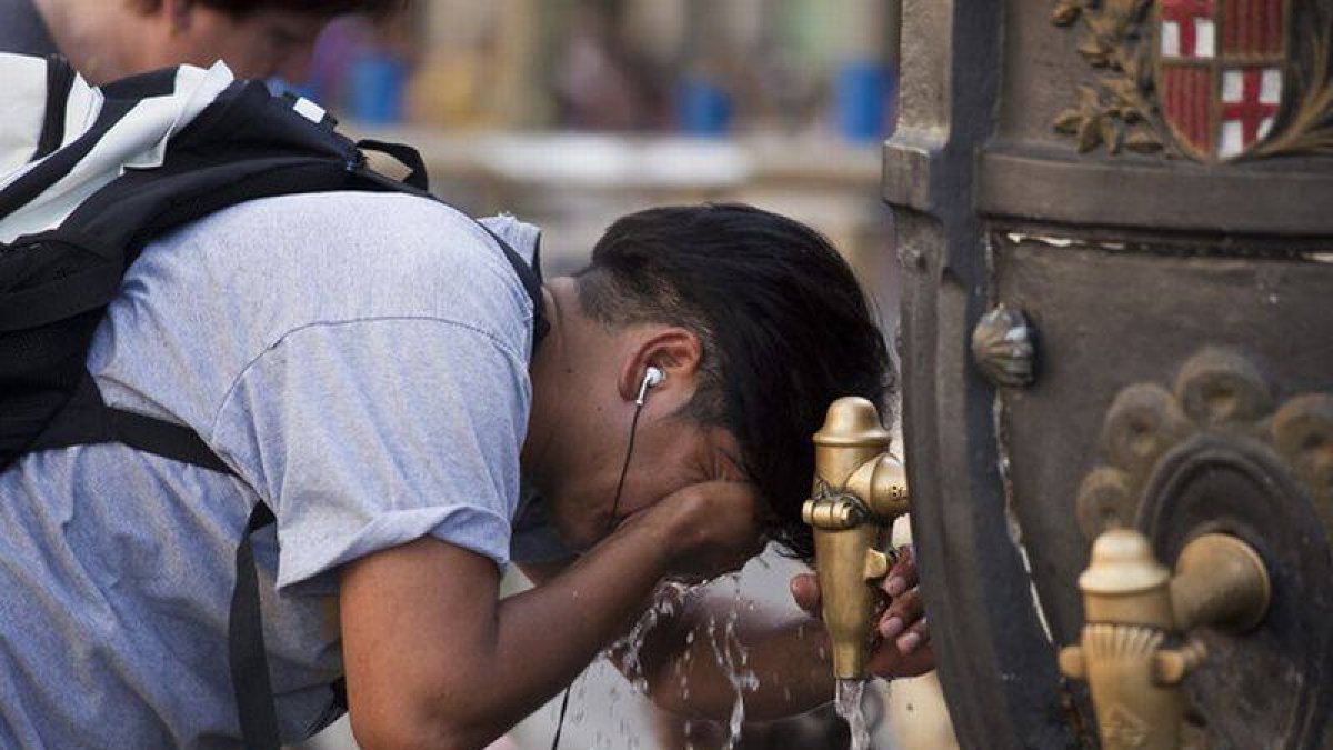 Un turista se refresca en la fuente de Canaletes durante una ola de calor.