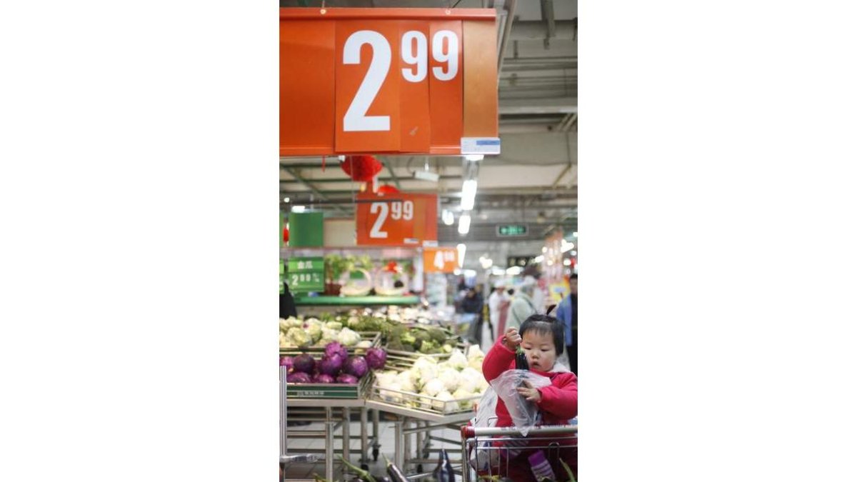 Un niña, ante el mostrador de frutas y verduras de un supermercado.