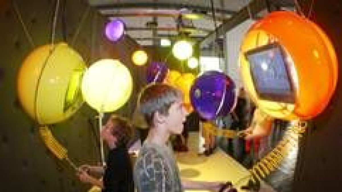 Unos niños juegan a los videojuegos con ordenadores que cuelgan del techo