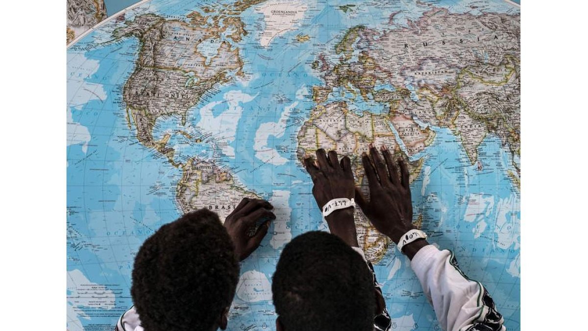 Dos personas inmigrantes localizan en el mapa su lugar de procedencia. EFE