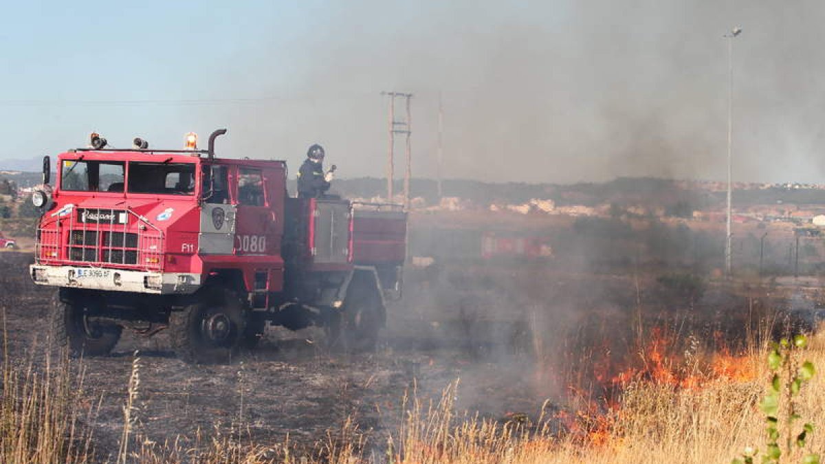 Bomberos sofocando un incendio, este verano, desde el vial de acceso de Trobajo a la LE-30.