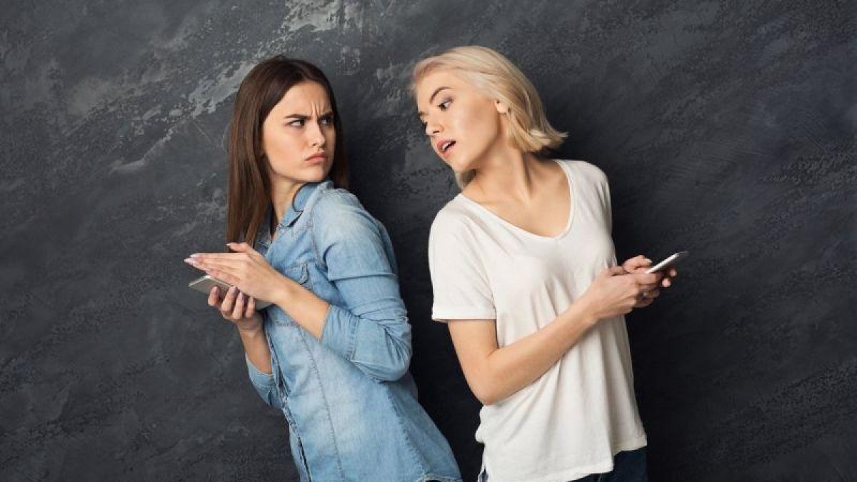 Una chica espía el móvil de su amiga.