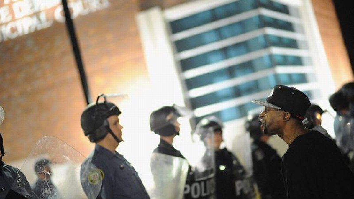 Un ciudadano protesta ante un cordón policial frente a la comisaría de Ferguson, este miércoles.