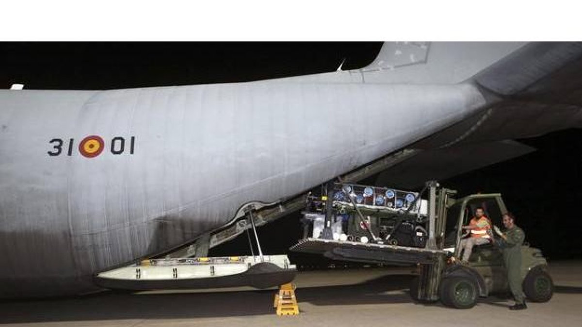 Dos militares bajan la camilla-burbuja del avión español que ha llegado al aeropuerto de Freetown para repatriar al médico misionero leonés