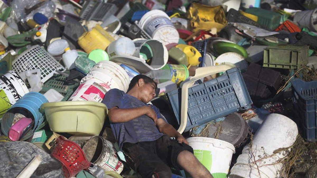 Un joven descansa sobre el vertedro de basura en el que recoge plásticos y metales.