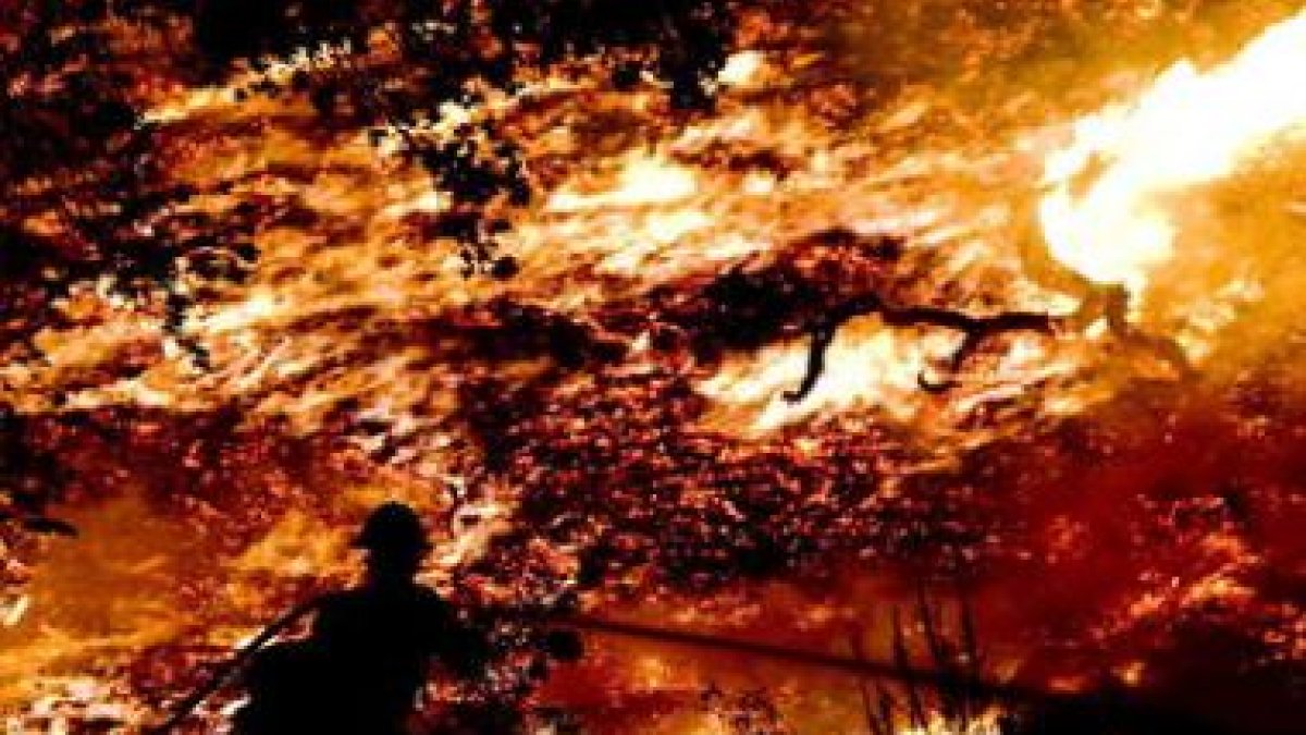 Un grupo de bomberos intenta contener un incendio forestal en las montañas.