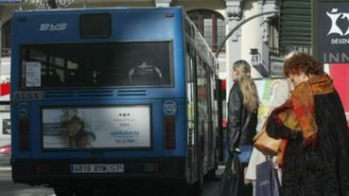Varios viajeros esperan en la parada de autobuses de la plaza de Santo Domingo.