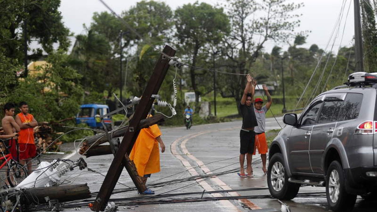 Unos niños levantan cables para que pase un coche. F. R. MALASIG
