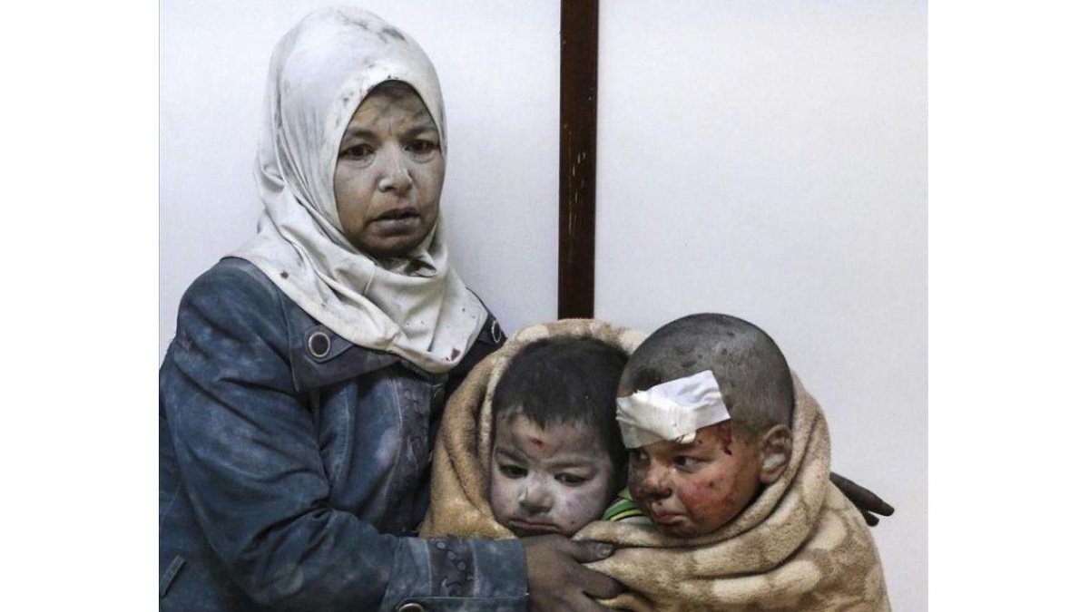 Una mujer abraza a sus hijos tras resultar todos heridos en un bombardeo en el barrio de Al Barze.