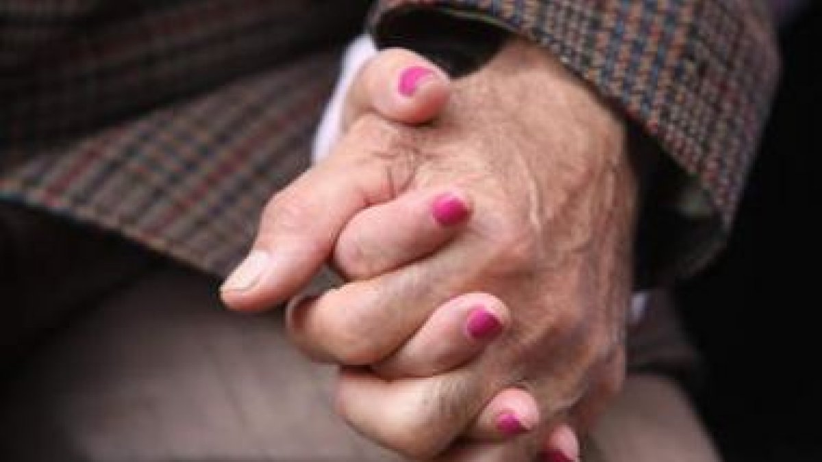 Dos ancianos se dan la mano en una romería en Garrafe de Torío .