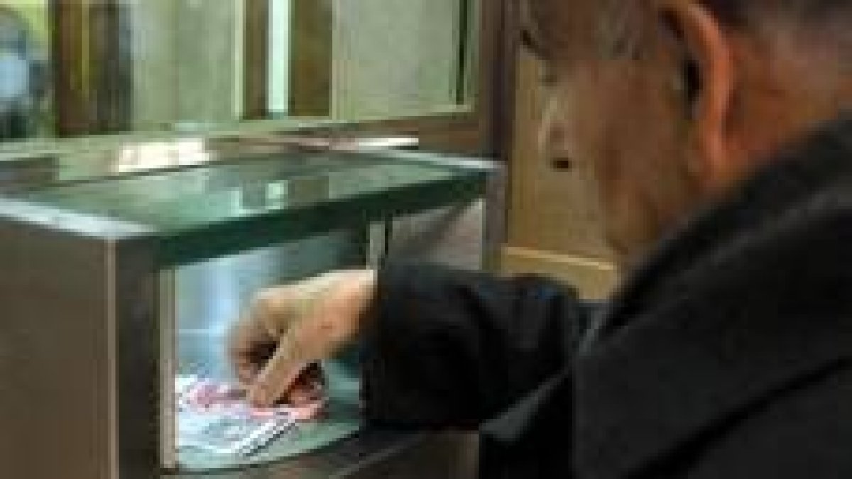 Un hombre retira dinero de una ventanilla de una entidad bancaria