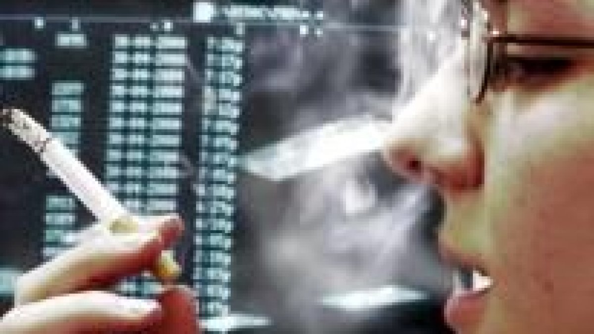 Una joven fuma un cigarrillo mientras trabaja frente a un ordenador