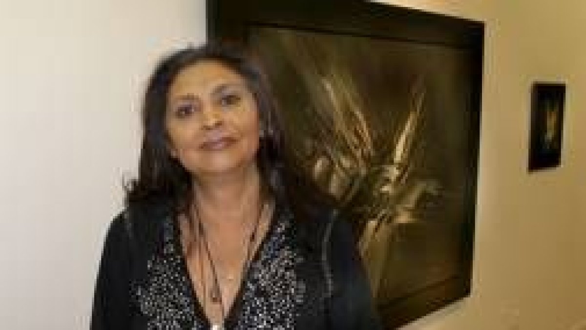La hija del artista, Kuki Viola, ante uno de los lienzos que pueden verse en Ármaga