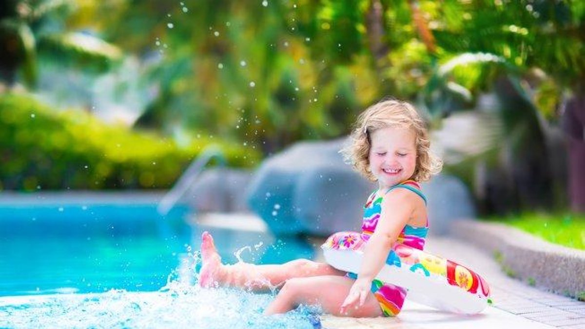 Una niña pequeña jugando en la piscina.