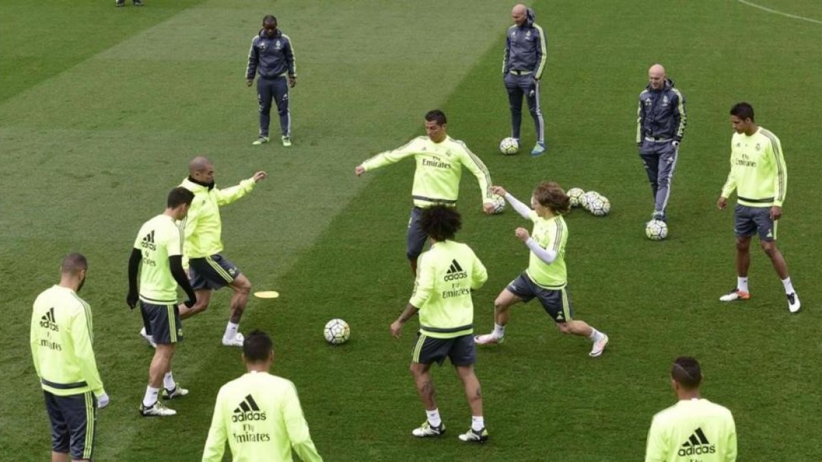 Zidane observa los movimientos de sus jugadores en el entrenamiento de este viernes en Valdebebas.