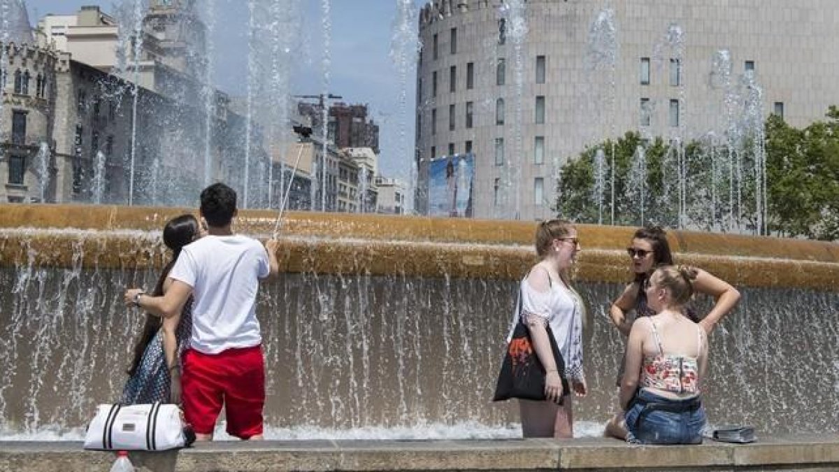 Unas personas se remojan en una fuente este verano en plena ola de calor