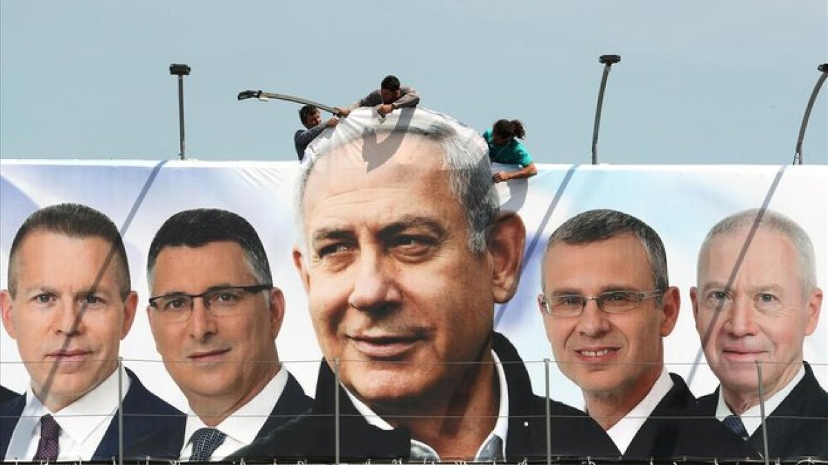 Un grupo de operarios trabaja en una valla publicitaria de propaganda electoral en la que aparece Netanyahu con candidatos de su partido, el Likud, en Jerusalén.