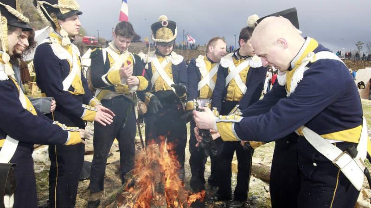 Un recreador escurre los guantes mientras sus compañeros tratan de calentarse las manos en una hoguera encendida tras la tormenta.