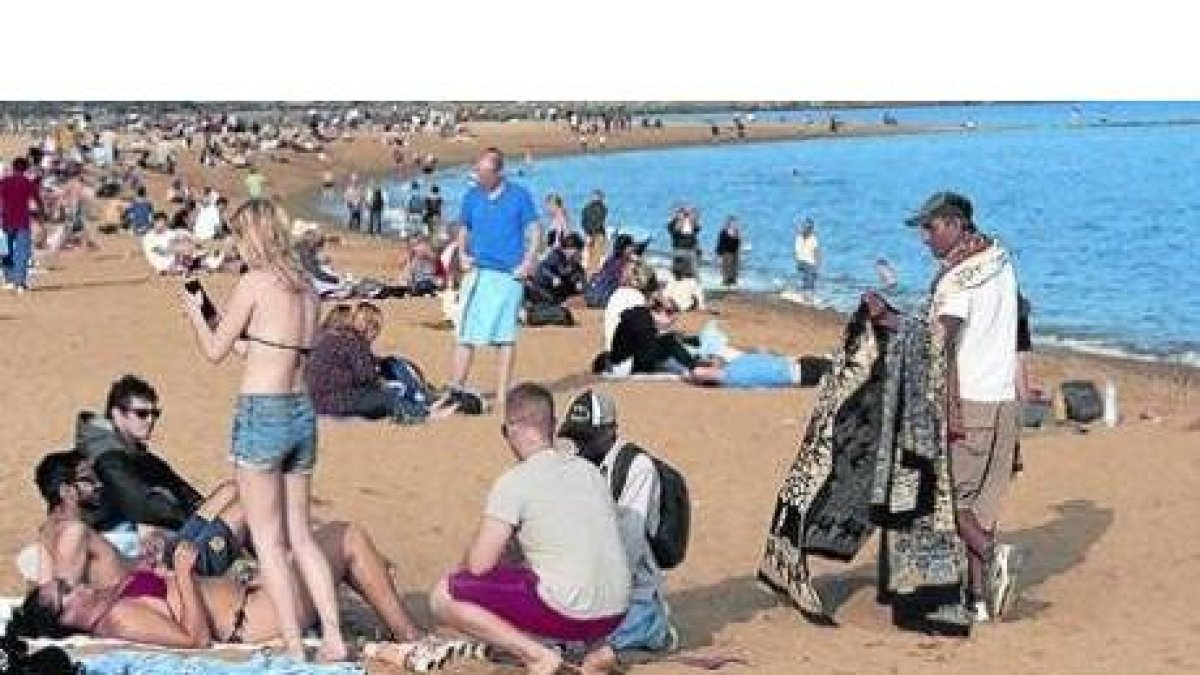Turistas en la playa de la Barceloneta, ayer, aprovechando un día radiante.