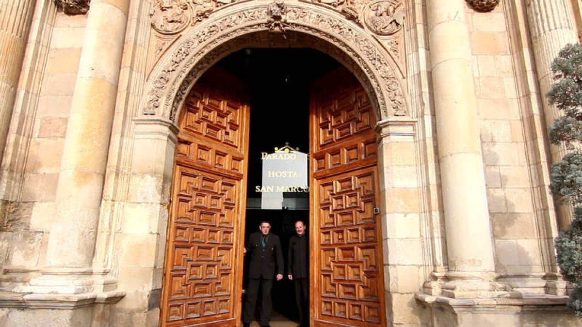 Dos mozos de Paradores en el momento del cierre de la entrada principal del hostal San Marcos. PARADORES