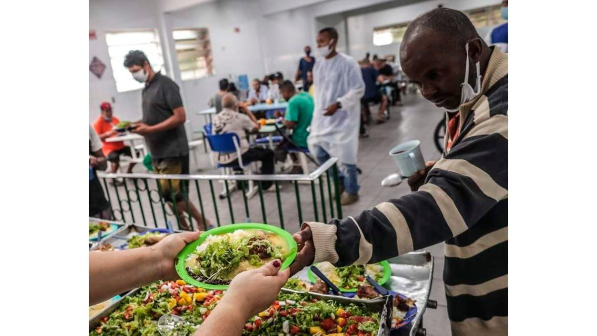Una persona entrega alimentos a un necesitado. ANDRÉ COELHO