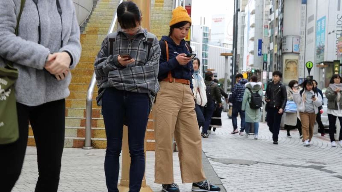 Jóvenes utilizan el móvil en las calles del barrio de Shibuya, en Tokio, que inspira a las marcas españolas.