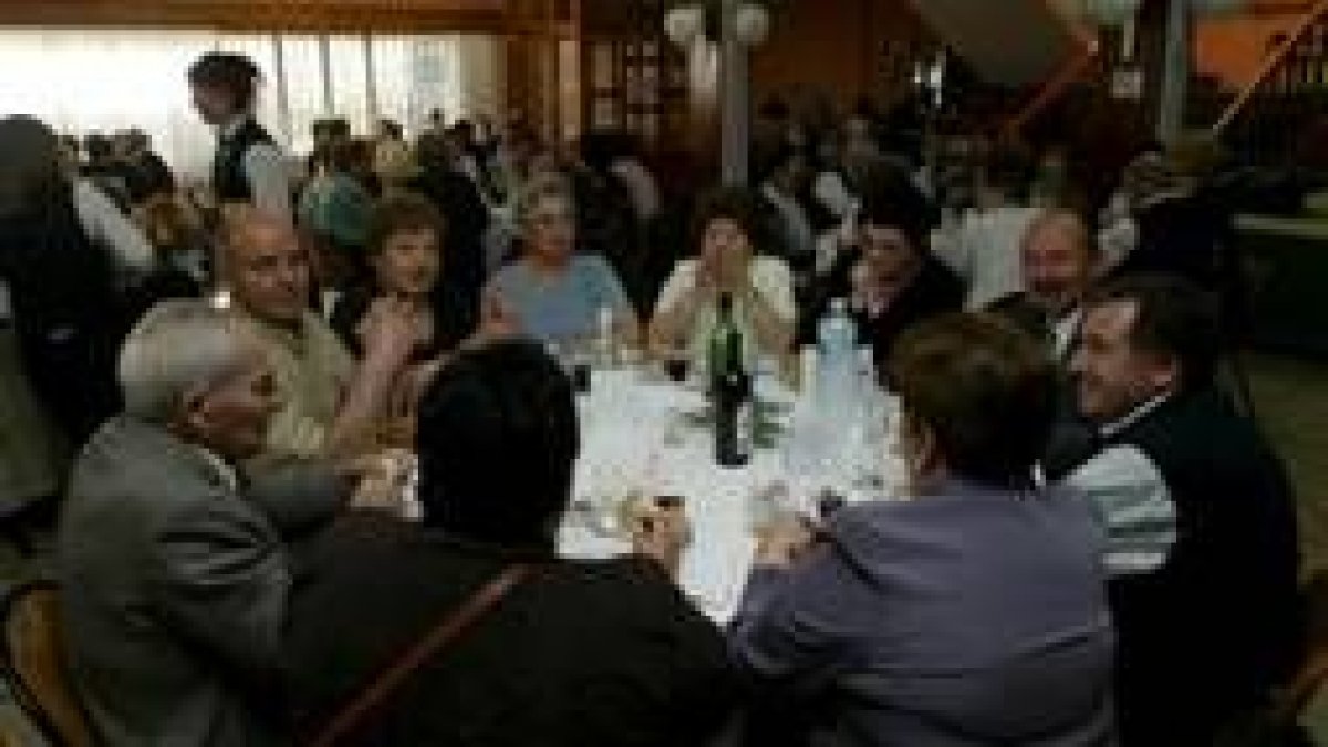 Los asistentes al acto festivo disfutan con el menú mientras intercambian opiniones