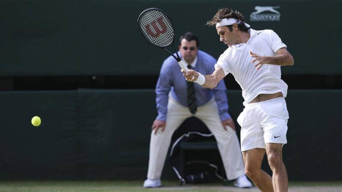 El tenista suizo Roger Federer devuelve una bola al canadiense Milos Raonic durante su encuentro de semifinales del torneo de tenis de Wimbledon, disputado en el All England Club en Londres (Reino Unido) hoy, viernes 4 de julio del 2014.