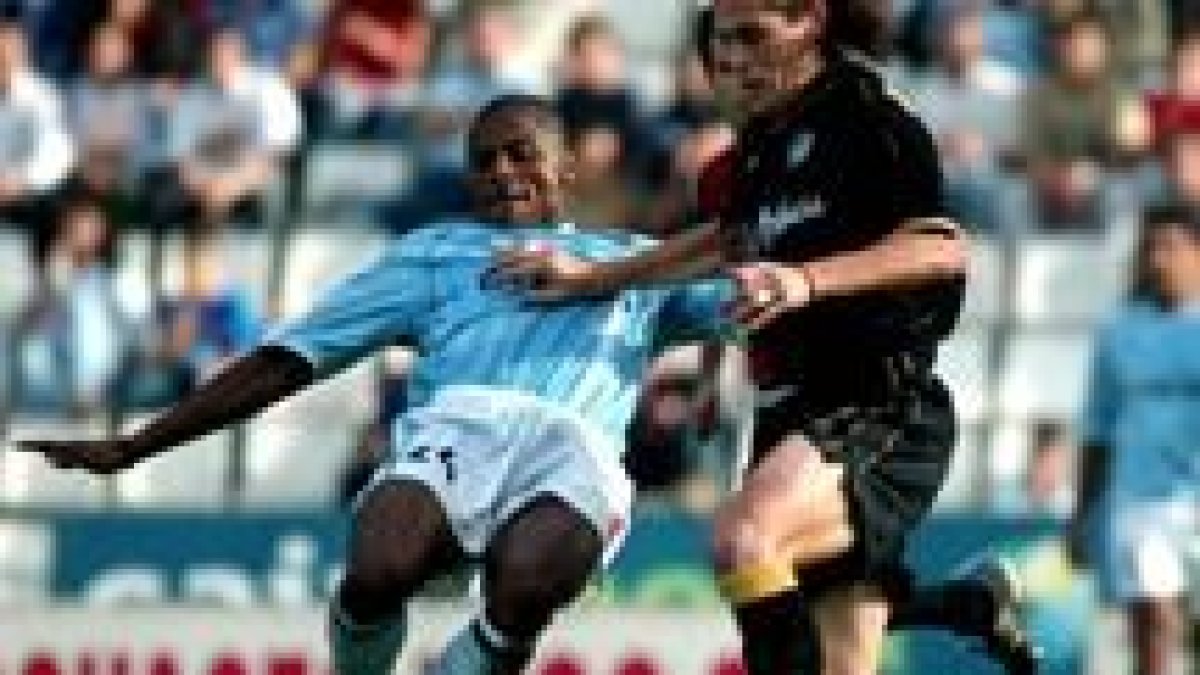 Catanha intenta alcanzar un balón ante la presencia de un jugador del Málaga en el partido de ayer