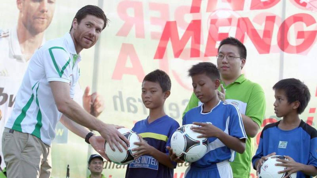 Alonso entrega balones de fútbol a jóvenes locales.