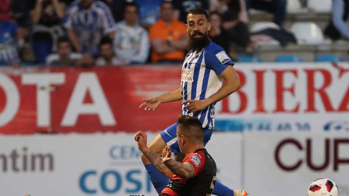 Carlos Bravo, de pie, se lleva el balón ante un contrario en un lance del encuentro. L. DE LA MATA