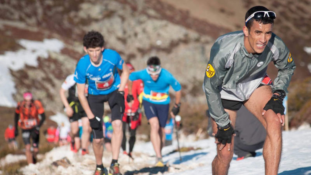 Una larga fila de corredores sube entre la nieve del vertical al Bóveda en la imagen de la izquierda. A la derecha avituallamiento y la labor de los voluntarios.