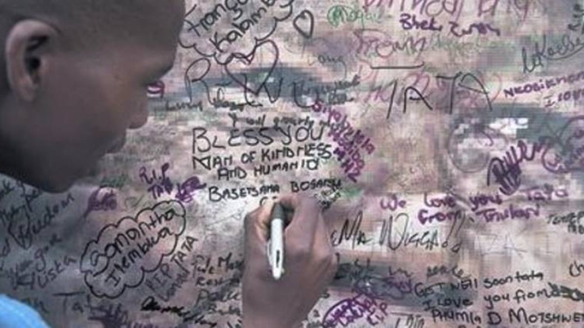 Un vecino de Soweto firma una condolencia en un póster en las afueras de la vieja casa de Mandela.