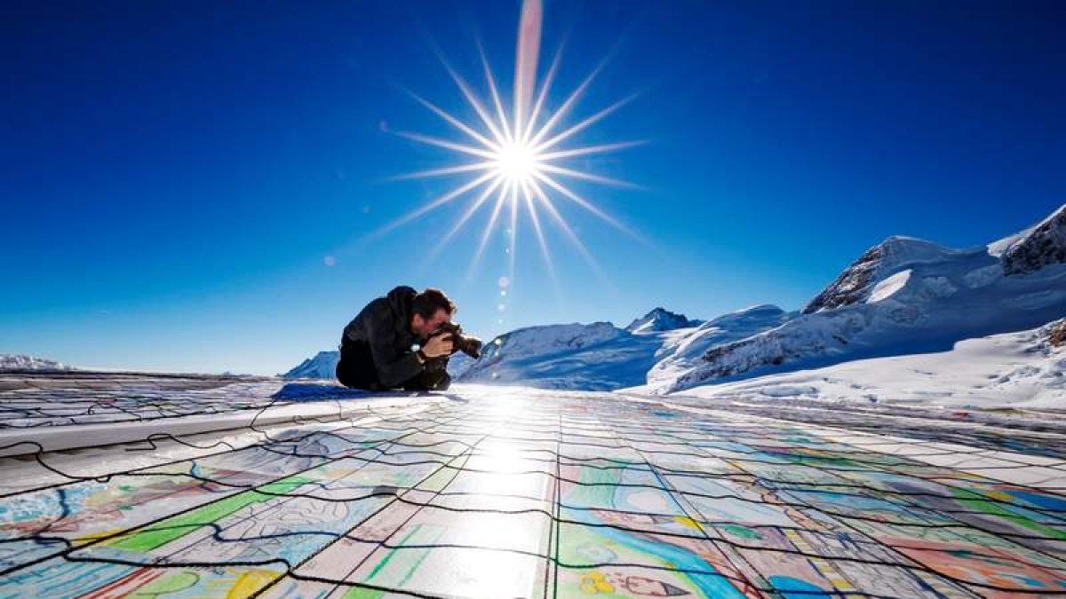 Un hombre fotografía una postal gigante compuesta por contribuciones individuales con mensajes de lucha contra el calentamiento global en el glaciar Aletsch en Jungfraujoch, en Suiza.