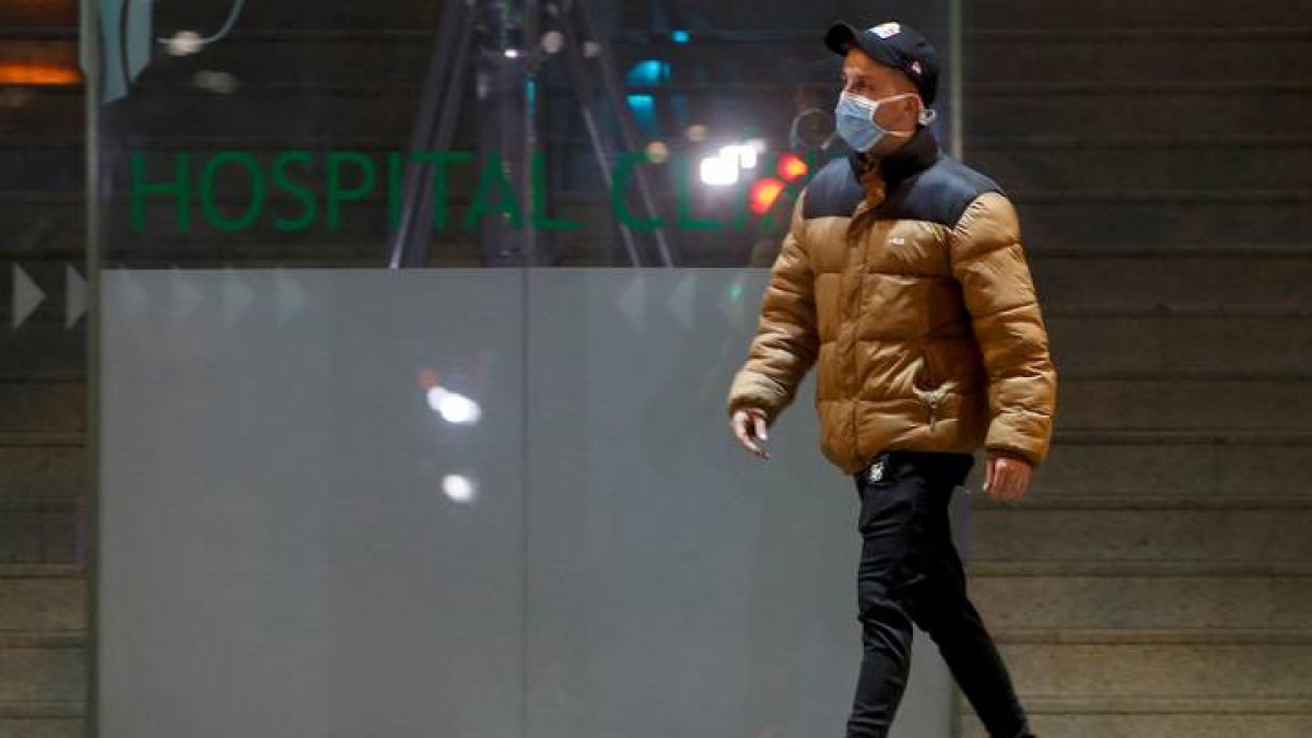 Un joven con mascarilla a su paso por el Hospital Clínic de Barcelona. QUIQUE GARCÍA