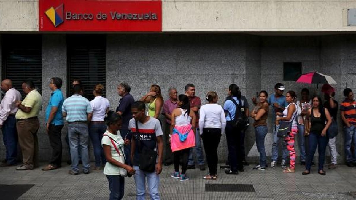 Ciudadanos venezolanos hacen cola en una cajero automático en una sucursal bancaria en Caracas, el viernes.