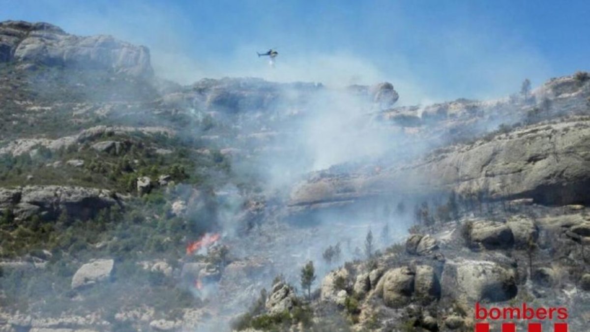 Descarga de agua de un helicóptero sobre las llamas del pantano de Margalef.