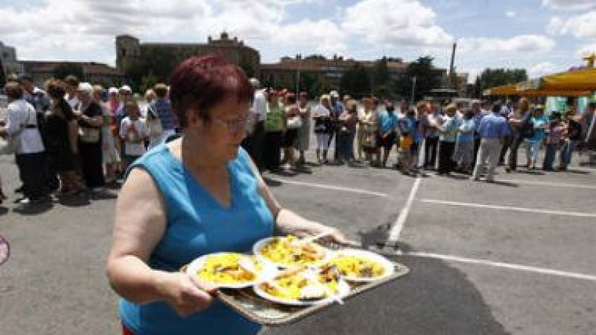 Una mujer lleva varios platos de paella durante la jornada de convivencia vecinal en León.