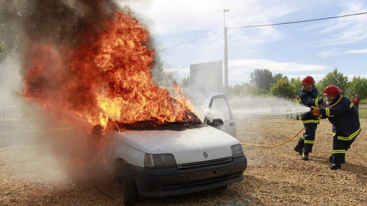 Los bomberos sofocan el fuego tras el simulacro de accidente y rescate de las víctimas.