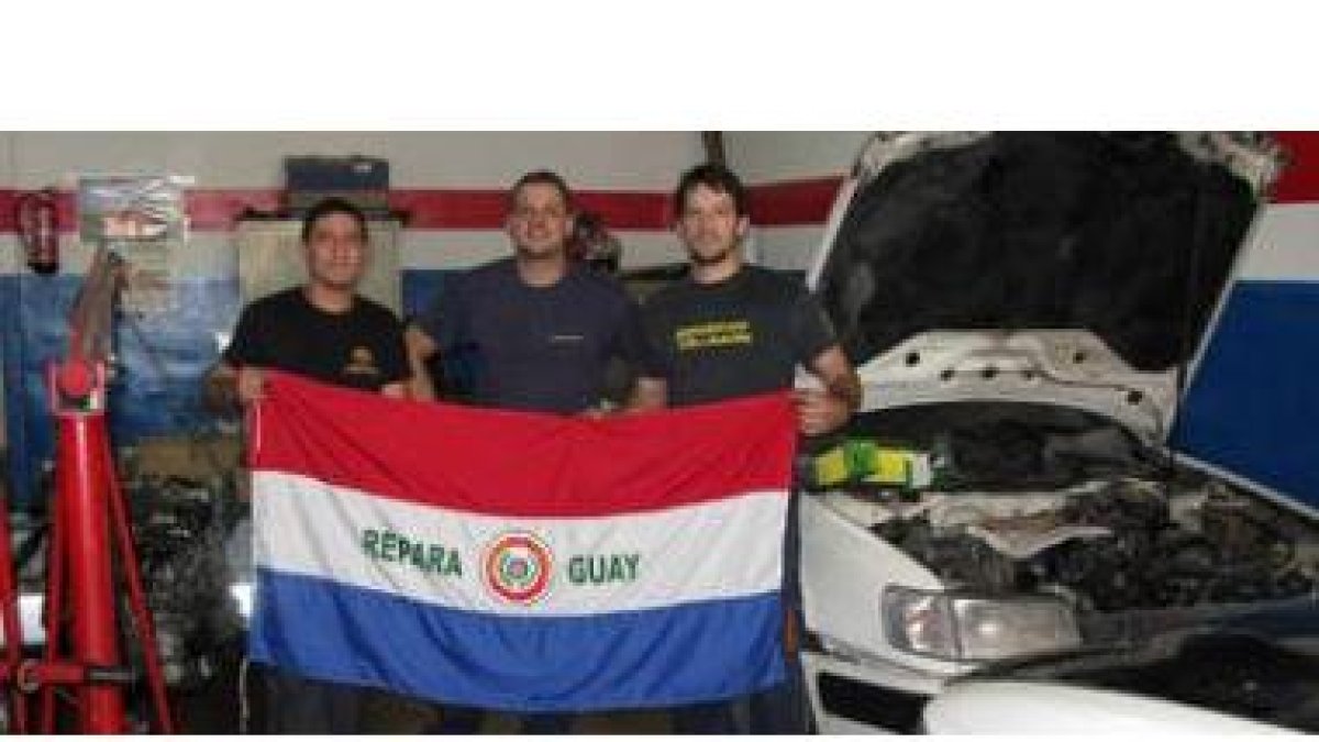 Los aficionados paraguayos Javier, Marcos y Óscar en el taller de reparación de coches.