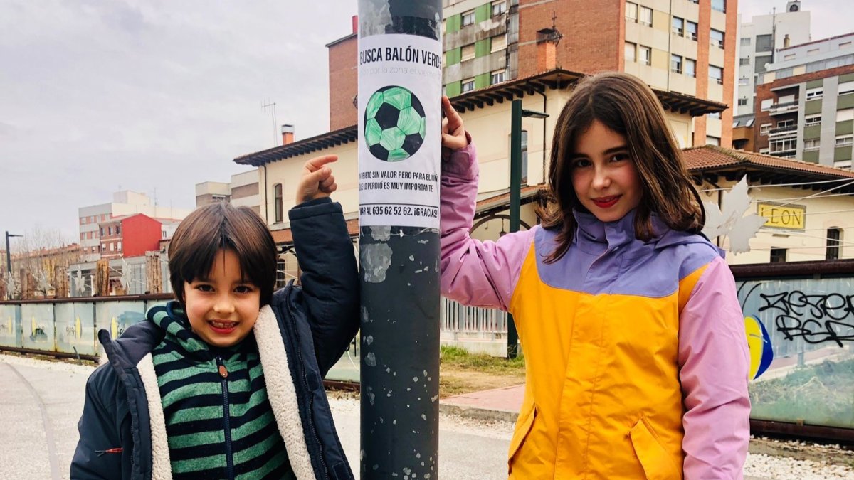 Jero y su hermana Clara, junto a uno de los carteles que ha colocado en una farola de la zona de Feve. DL