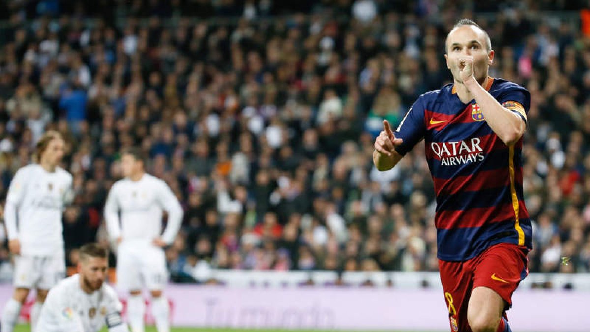 Andrés Iniesta celebra la consecución del tercer gol del Barça, mientras los madridistas Modric, Sergio Ramos y Cristiano Ronaldo se muestran abatidos al fondo.