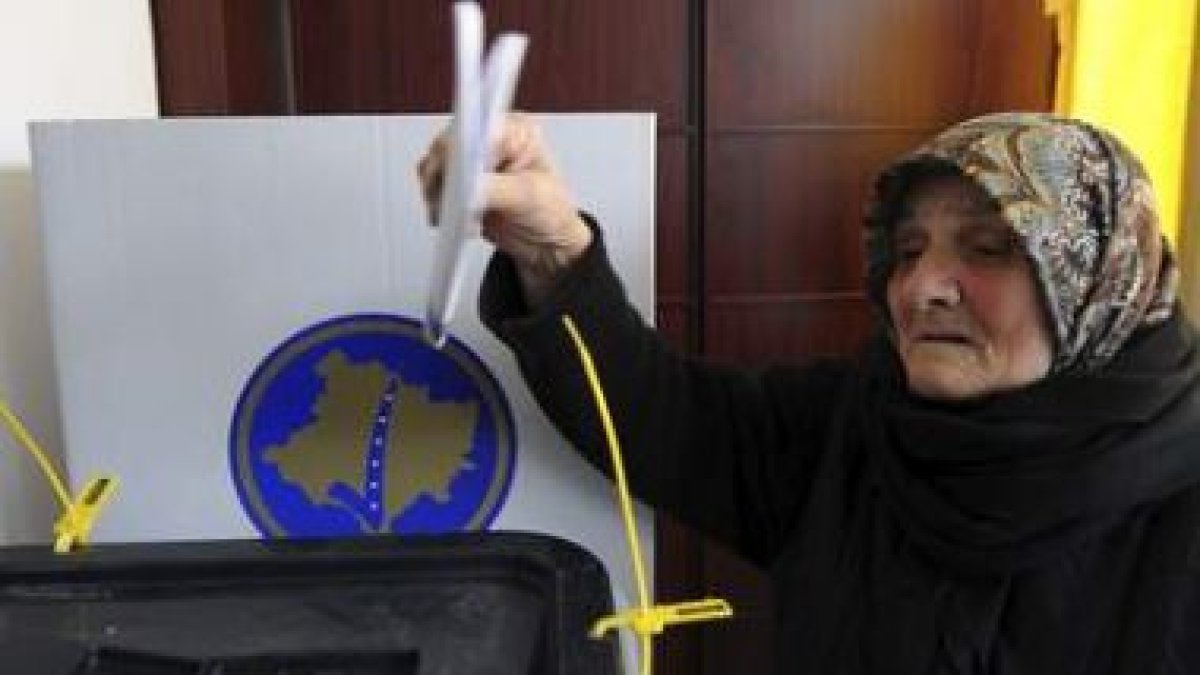 Una anciana deposita su voto en la urna.